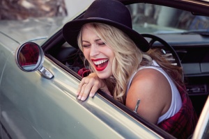 Young woman leaning out of car window, laughing